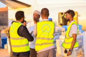 Electoral commission staff in marked vests unload polling materials from an aircraft ahead of the Hirshabelle vote on 20 August