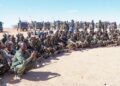 North East State soldiers seated with their weapons before a line of technicals, the force whose ranks include men recruited in Sanaag