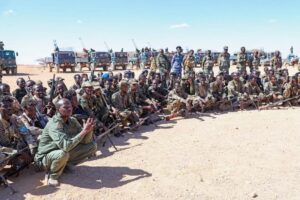 North East State soldiers seated with their weapons before a line of technicals, the force whose ranks include men recruited in Sanaag