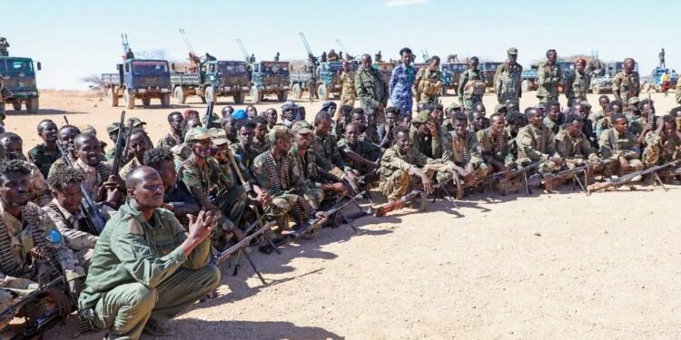 North East State soldiers seated with their weapons before a line of technicals, the force whose ranks include men recruited in Sanaag