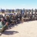 North East State soldiers seated with their weapons before a line of technicals, the force whose ranks include men recruited in Sanaag
