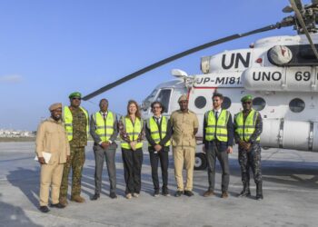 UNSOS, Somali and African Union personnel beside a United Nations helicopter at Mogadishu airport