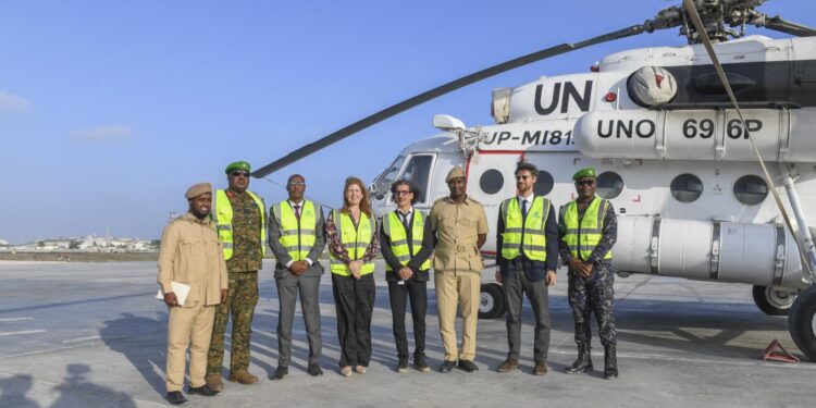 UNSOS, Somali and African Union personnel beside a United Nations helicopter at Mogadishu airport