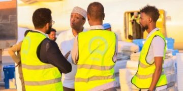 Electoral Commission staff in marked vests with polling materials beside an aircraft, the body that has set Somalia's federal vote for 15 May 2027